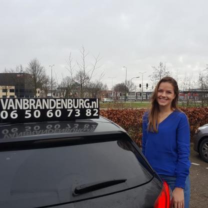 Geslaagde leerling bij de lesauto na het praktijkexamen