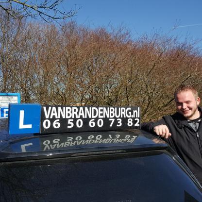 Geslaagde leerling poseert bij de lesauto