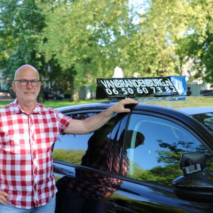 Geslaagde leerling bij de lesauto van de rijschool