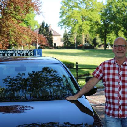 Geslaagde leerling viert het behaalde rijbewijs bij de lesauto