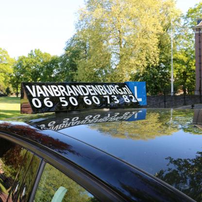 Geslaagde leerling naast de lesauto